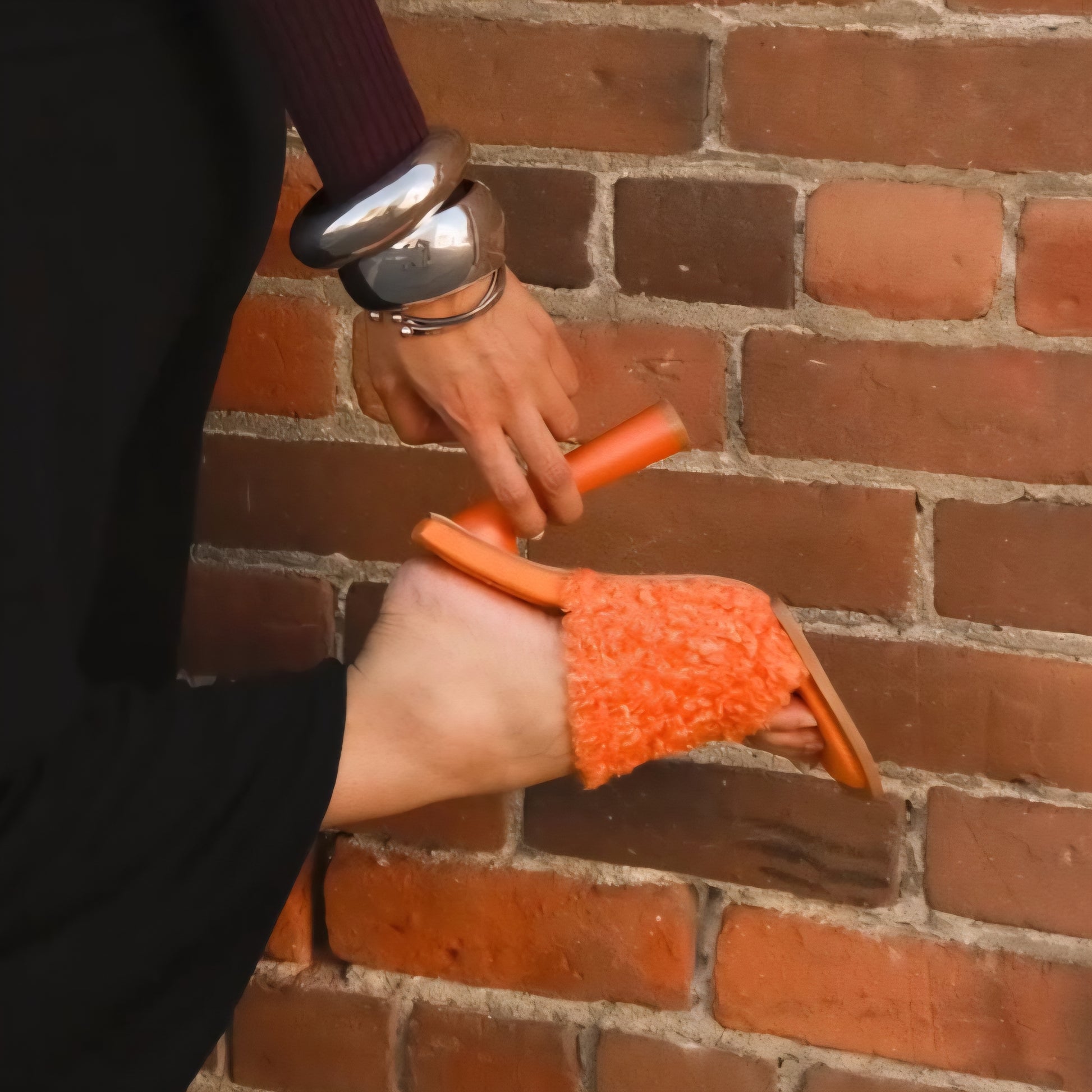 Person applying a product to a brick wall using an orange tool.