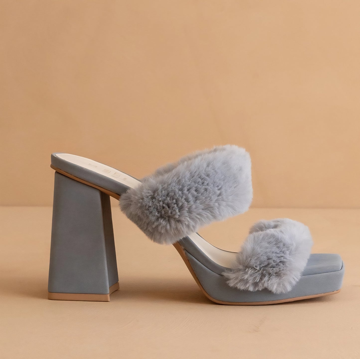 Light blue sandal with fluffy pom-poms on a beige background