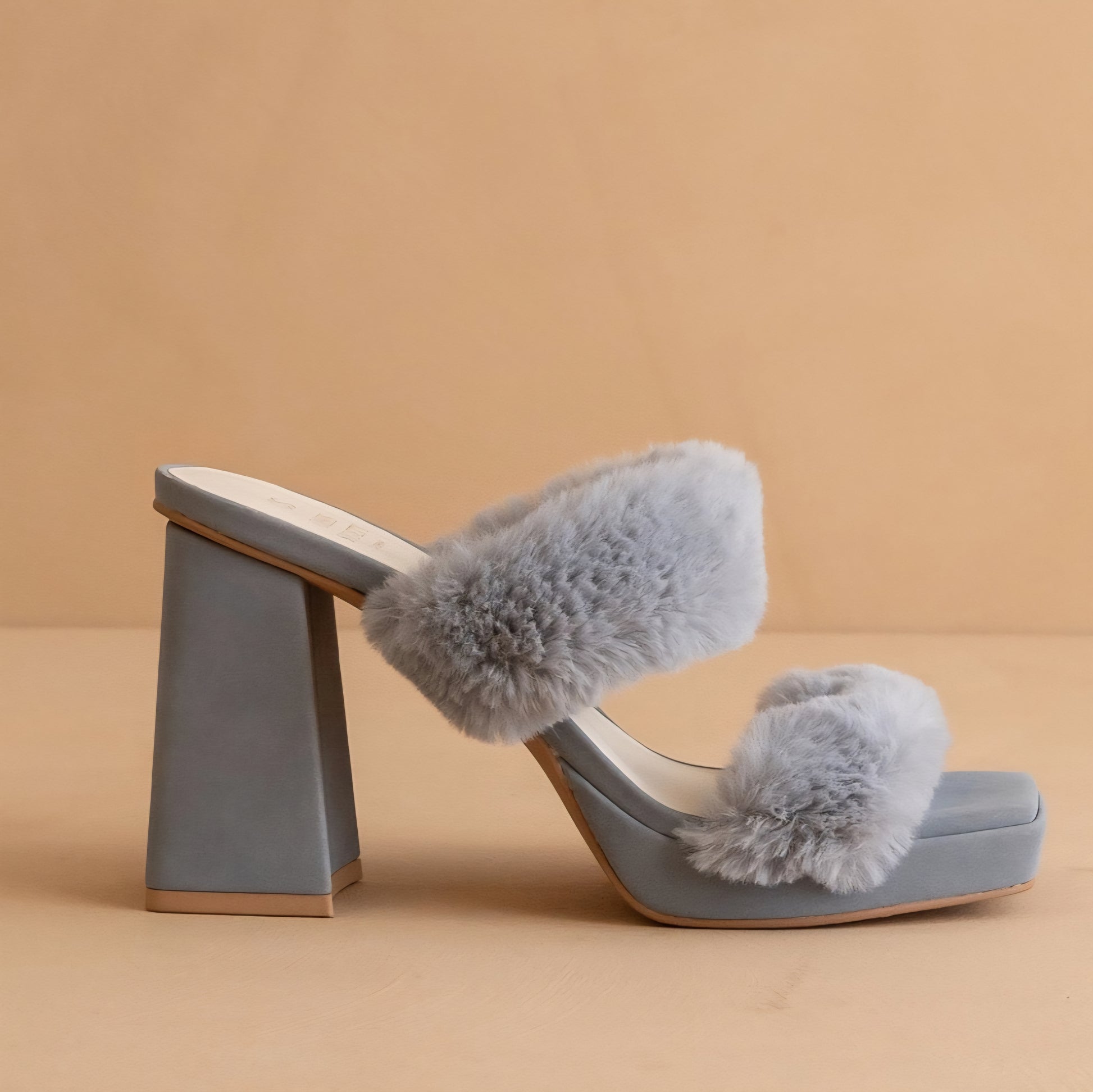 Light blue sandal with fluffy pom-poms on a beige background