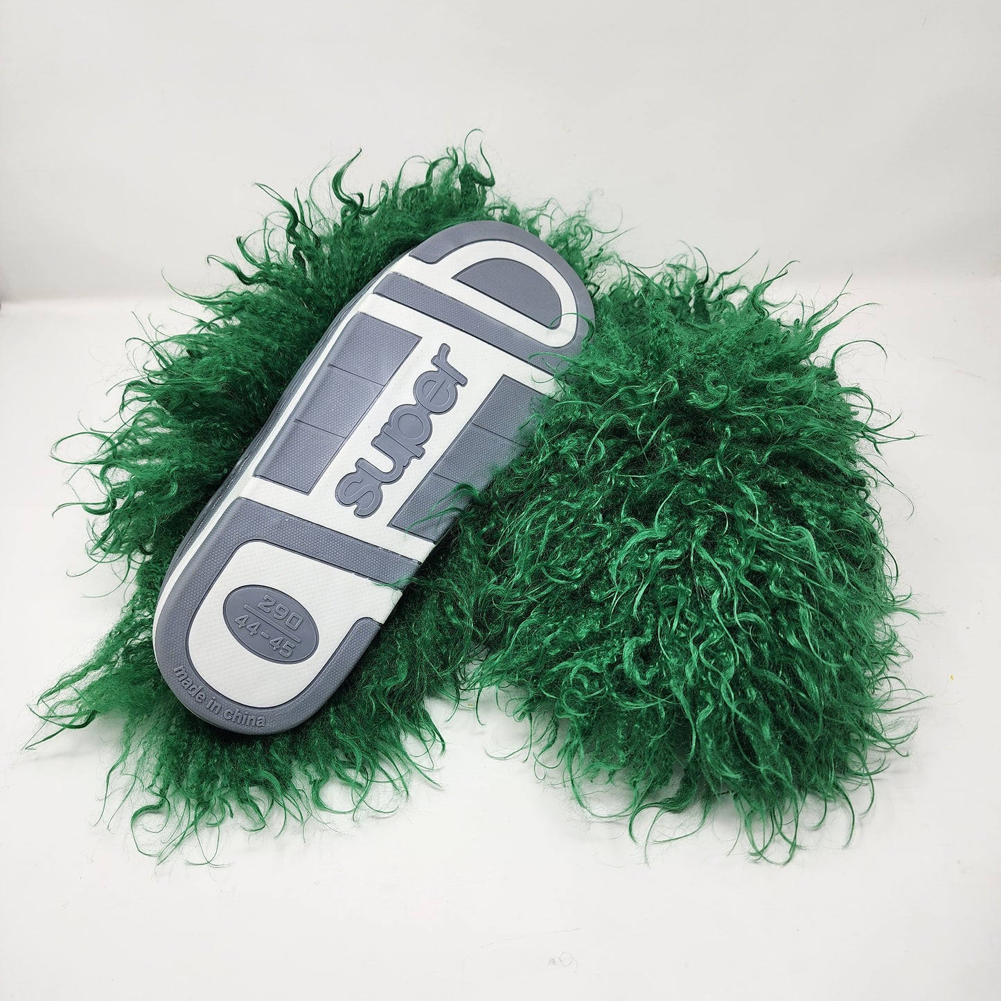 Green fluffy slippers with gray sole on a white background