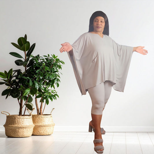 Woman in a light gray outfit standing in front of potted plants on a white background
